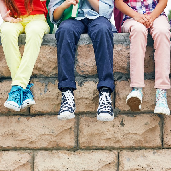 Schulkinder sitzen auf einer Mauer